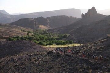 Amazing mountain landscapes of Jebel Saghro with volcanic rocks eroded by wind and time and little silhouettes of group of trekking tourists. Atlas, Anti Atlas, Morocco © Iwona