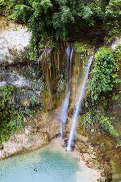 Woman floating in the lagoon near tall waterfall, Philippines