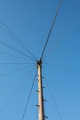 A single pole with many cables around connected into one knot against the sky. . High quality photo