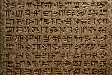 Close up of ancient cuneiform script carved into a stone tablet with detailed symbols visible