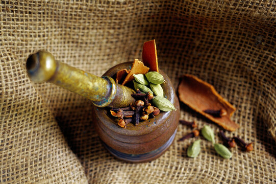 Indian spices, cardamom cinnamon tejpat and clove in mortar and pestle, India