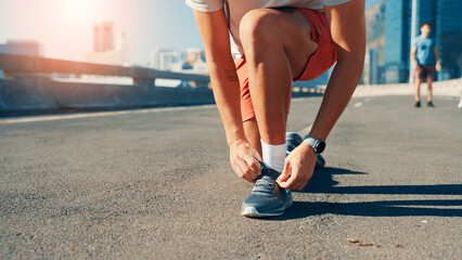 Fototapeta premium Person, hands or tying shoes in city street for fitness preparation, workout or exercise. Closeup, active or runner getting ready with tie or laces on road for cardio training, sprint or race in town