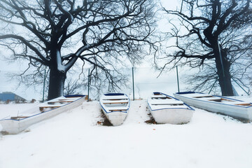 blue sad winter landscape with wooden boats in snow