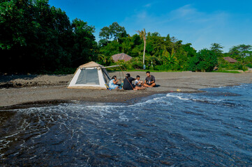 A calm family meal by the beach as waves roll in front of their camping tent