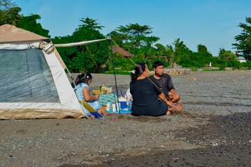 Relaxed family meal as they take in the view of the sea while sitting in front of their tent