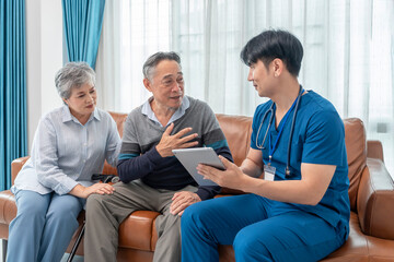 scene of senior patient talking to a visiting nurse who using tablet computer giving advice elderly man and family for self health care at home