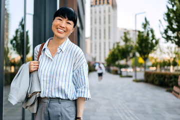 Smiling businesswoman walks confidently down a city street on a sunny morning