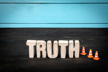 Truth. Concrete Word with Safety Cones on Dark Wood and Blue Background