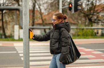 Girl Pressing Traffic Light Button At Pedestrian Crossing In Spring