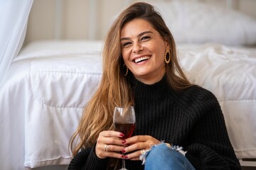 Plakat Young woman smiling with red wine indoors.