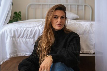 Plakat Woman in cozy room sitting by the bed.