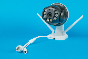 Modern Wireless Security Camera on Blue Backdrop with Ethernet and Power Cables