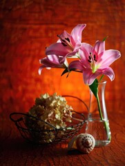 Pink lilies and dried flowers in a vase with a seashell on a wooden table