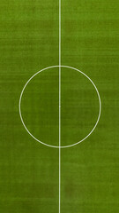Aerial perpendicular closeup of the midfield circle in an empty synthetic grass football field. Here the kick off is taken in a game of soccer.