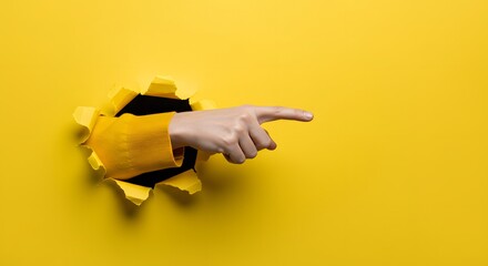 hand pointing through torn hole on yellow paper background