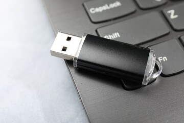 Flash drive and laptop on gray table, closeup