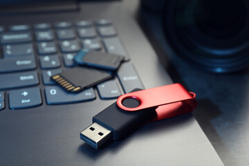 SD memory cards, USB flash drive and laptop on dark grey table, closeup
