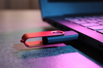USB flash drive connected to laptop on dark grey table, closeup