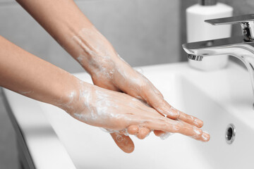 Fototapeta premium Woman washing hands at sink in bathroom, closeup