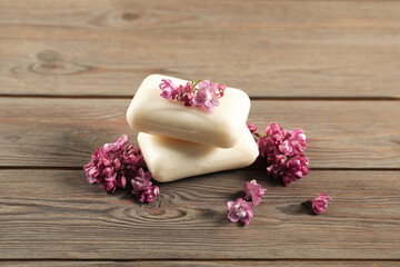Soap bars and lilac flowers on wooden table, closeup