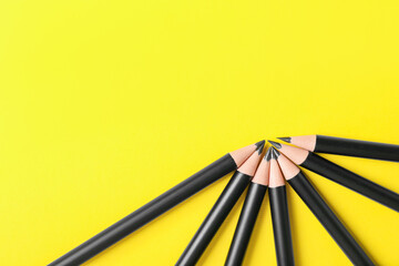 Many sharp graphite pencils on yellow background, flat lay. Space for text