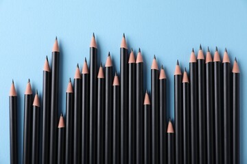 Many sharp graphite pencils on light blue background, flat lay