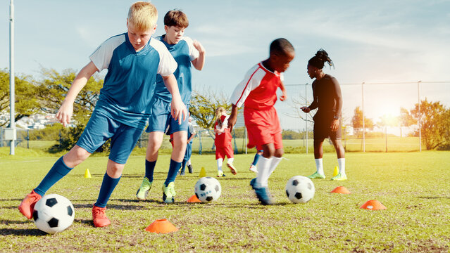 Playing, soccer player and children with ball, kick and athlete with energy for practice in morning. Sports field, football and kids with sportswear for game, growth and development with fitness