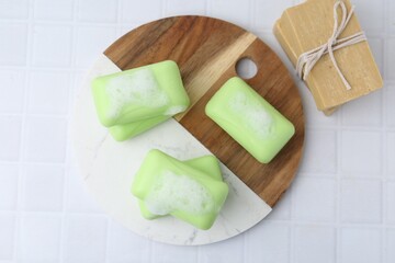 Soap bars with foam on white table, top view