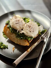 Poached egg on a piece of bread with spinach on the black plate
