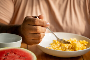 Costa Rican tourist having a relaxing breakfast with scrambled eggs, watermelon and coffee in Costa Rica