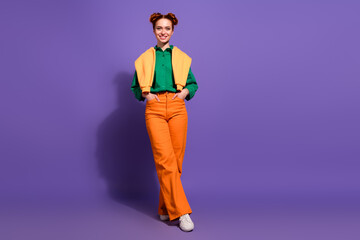 Stylish young woman in colorful casual outfit with red hair and charming smile against vibrant purple background