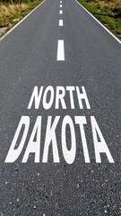 Empty road in north dakota with painted state name on asphalt