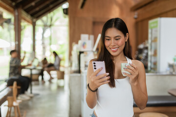 woman drinking coffee in cafe and using mobile phone