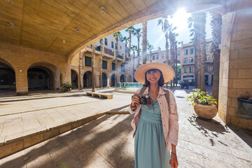 Female photographer with camera shooting in the city. Young female photographer aiming the lens and...