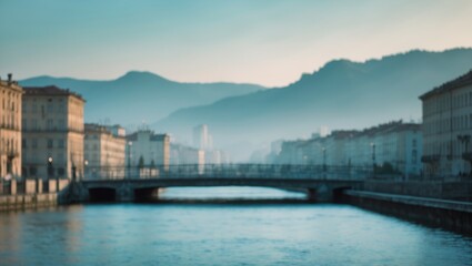 Fototapeta premium Cityscape with river and mountains in the background, featuring historic buildings and a bridge. Urban landscape with natural scenery.