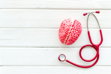 Human brain anatomical model with red stethoscope, top view. Mental health concept.