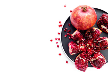 Fresh ripe pomegranate with cut in half and pieces on plate to eat, top view.