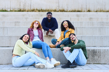 Happy multi ethnic friends sitting and relaxing on urban steps