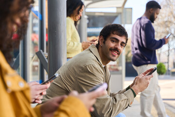 Young man using mobile phone while waiting at bus stop