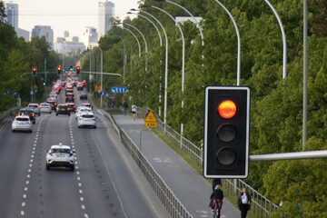 A red traffic light on a blurred road with a car heading toward the city center, symbolising a slowing economy, traffic, recession, or transportation issues.