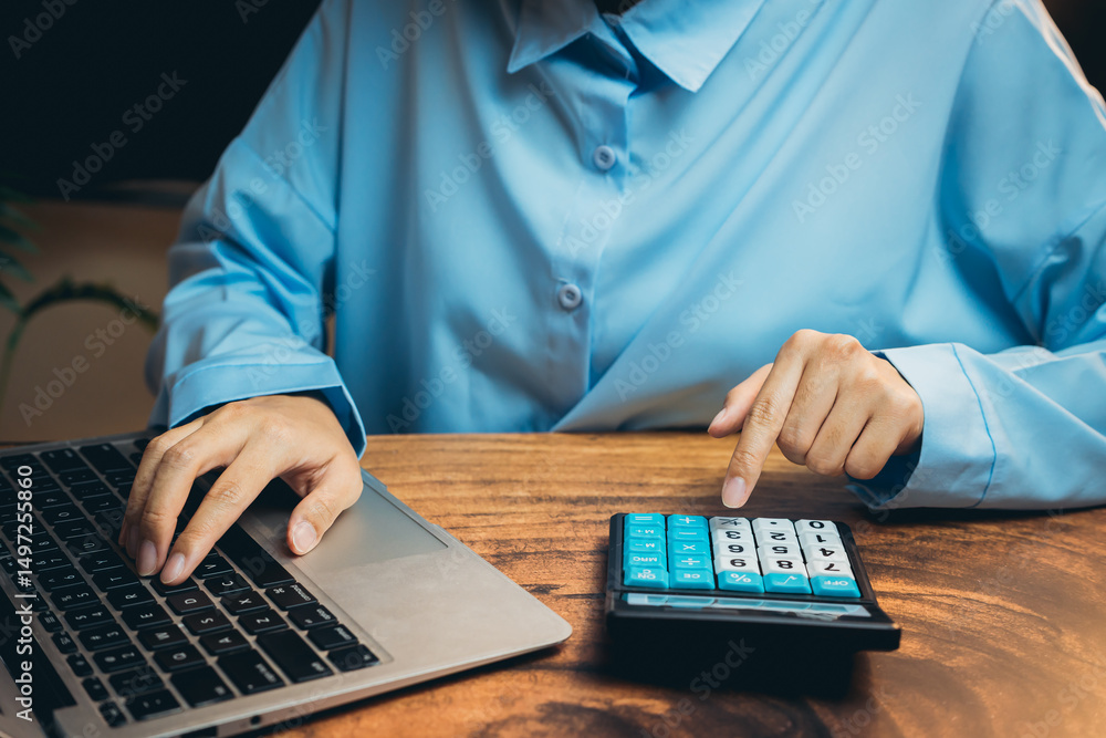 Poster professional user working on laptop while using calculator for financial calculations in modern work
