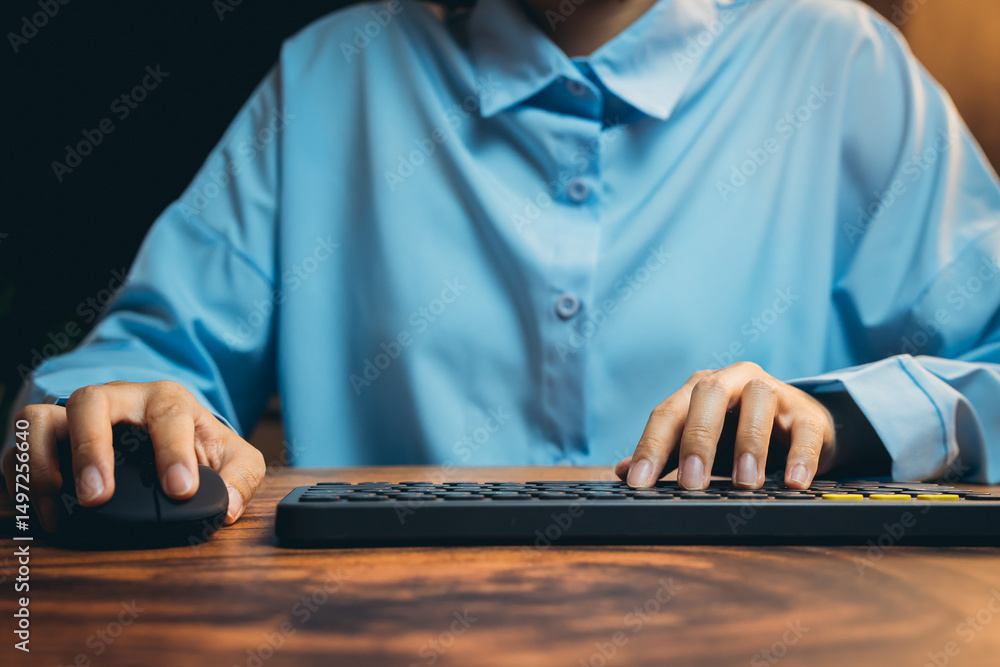 Poster close-up view of hands using computer mouse and keyboard on wooden desk in cozy office setting
