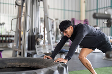 Tire Push Workout. A man pushing a heavy tire for strength and endurance training.