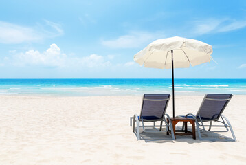 Beach chairs and umbrella on white sandy beach with turquoise sea. Summer vacation and travel concept.
