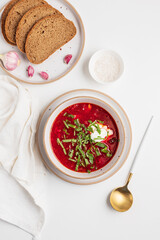 Traditional Ukrainian borscht with sour cream, garlic and rye bread on white table. Top view