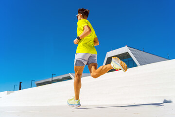 Energetic jogger races towards the bright blue sky in a vibrant cityscape on a sunny morning