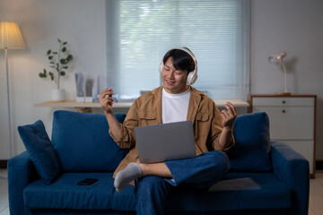 Fototapeta premium A man is sitting on a blue couch with a laptop in front of him