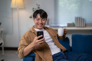 A man is sitting on a couch with a cell phone in his hand