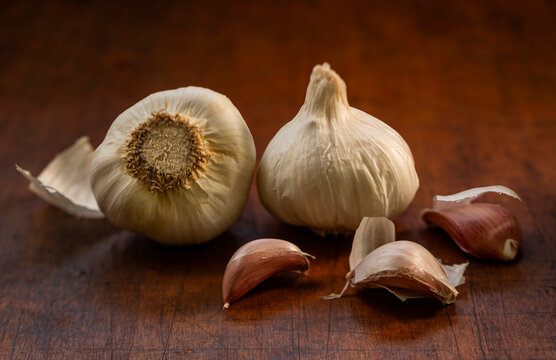 Whole and pealed raw garlic on wooden cutting board