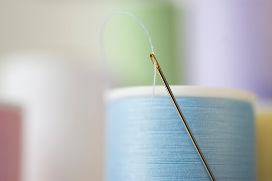 Studio shot of needle and spool of blue thread